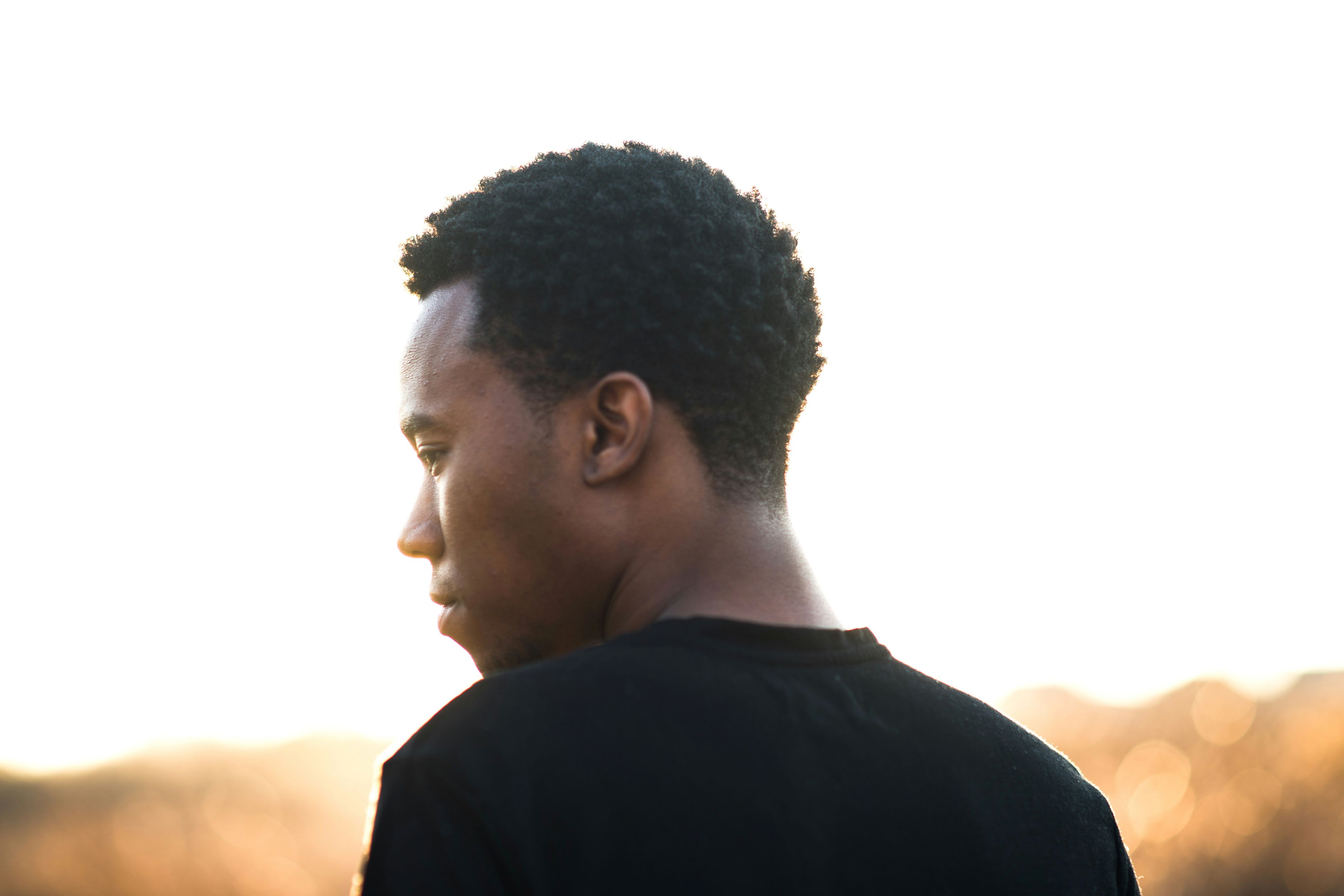 A photograph of the back of a Black man wearing a black shirt looking to the left